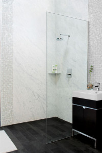 Bianca Carreaa Bolder Panels installed in a shower in the Stone Source - Tile Source International showroom. Includes the Bianco Carrera corner caddie and lava black slate on the floor